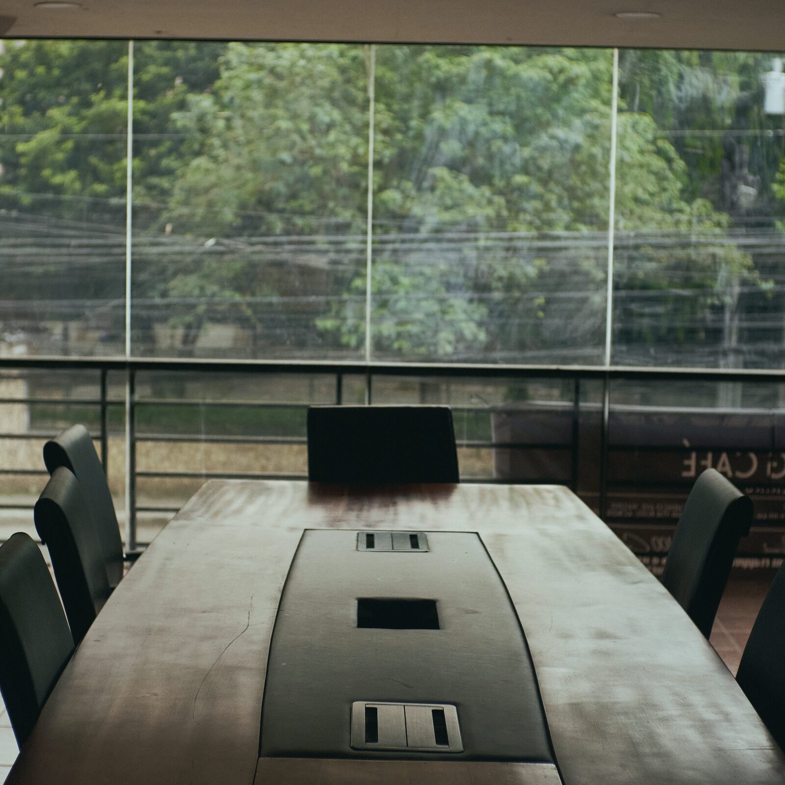 An empty meeting table with greenery outside the window